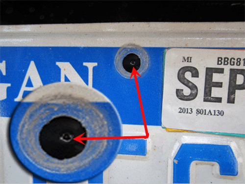 Center the license plate on the rear fascia and confirm that a dimple is visible in each of the license plate mounting holes.